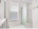 Bathroom featuring glass shower door, window with shade and gray cabinetry at 1131 Fern Ave, Orlando, FL 32814