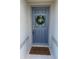 Charming blue front door adorned with a wreath and welcome mat at 1656 Aspen Ave, Davenport, FL 33837