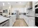 Modern kitchen featuring white cabinetry, granite countertops, stainless steel appliances, and wood-look tile flooring at 4223 Sunset Preserve Blvd, Orlando, FL 32820