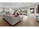 Bright, open-concept living room featuring wood floors, a large sectional, and sliding glass doors to the backyard at 4223 Sunset Preserve Blvd, Orlando, FL 32820