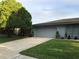 Charming home with mature trees, manicured lawn, and a well-maintained driveway leading to the garage at 5138 Andrea Blvd, Orlando, FL 32807