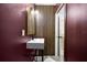 The half-bath features modern lighting and a mirror, accentuating the wooden detail behind the sink at 2337 Worthington Rd, Maitland, FL 32751