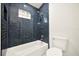 Contemporary bathroom featuring blue tiled shower, modern fixtures, and a white toilet at 2337 Worthington Rd, Maitland, FL 32751