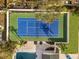 Aerial view of a vibrant blue and green tennis court with an adjacent pool in a well-landscaped yard at 2337 Worthington Rd, Maitland, FL 32751