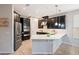 A modern kitchen features dark cabinets, stainless steel appliances, and a large island with quartz countertops at 1219 Verdant Glade Pl, Winter Park, FL 32792