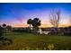 Backyard view with lush lawn, a black fence, and a tranquil lake at sunset at 1312 Blue Stem Ln, Winter Park, FL 32792