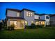 Rear exterior view of home featuring a lawn, and a covered patio with sliding glass doors at dusk at 1312 Blue Stem Ln, Winter Park, FL 32792