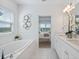 Bright bathroom showcases a soaking tub, double sink vanity, white marble tile, and a view to the bedroom at 1312 Blue Stem Ln, Winter Park, FL 32792