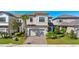 Two-story gray home featuring a well-manicured lawn, a palm tree, and a brick driveway leading to the garage at 1312 Blue Stem Ln, Winter Park, FL 32792