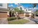 Tan townhome with two-car garage, palm trees, and manicured landscaping at 564 Woodland Terrace Blvd, Orlando, FL 32828