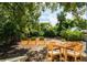 Outdoor dining area under shady trees, featuring a wood table and chair set and green landscaping at 1235 19Th St, Orlando, FL 32805