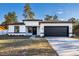 Charming single-story home featuring a black garage door, a white exterior, and a well-manicured front yard at 14962 Sw 39Th Cir, Ocala, FL 34473