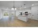 Bright, open-concept living space features wood floors, sliding glass doors, kitchen island, and modern light fixtures at 14962 Sw 39Th Cir, Ocala, FL 34473