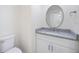 Well lit bathroom with updated vanity, granite countertop, and decorative round mirror at 10632 Whitestone Ct, Orlando, FL 32817