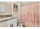 Bathroom with granite countertop, white cabinets, and pink shower curtain at 11237 Amber Ridge Dr, Zellwood, FL 32798
