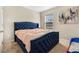 Blue upholstered bed with peach colored bedding in a bright bedroom at 11237 Amber Ridge Dr, Zellwood, FL 32798