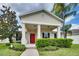 Beige house with red door, covered porch, and manicured landscaping at 4973 Pall Mall W St, Kissimmee, FL 34758
