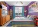 Purple bedroom with large bed, mid century modern dresser, and a large window at 1021 Siena Park E Blvd # 103, Kissimmee, FL 34747
