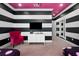Stylish bedroom with black and white striped walls, pink chair, and TV at 1261 Radiant St, Reunion, FL 34747