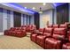 Luxury home theater room with comfortable red seating and a large projection screen at 1261 Radiant St, Reunion, FL 34747