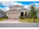 Two-story house with tan siding, a two-car garage, and a brick paver driveway at 285 Miro Dr, Davenport, FL 33837