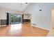 Open living room with wood flooring, slider to backyard, and view of kitchen at 4008 Crossroads Pl, Casselberry, FL 32707