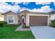 Tan one-story house with brown garage door and landscaped lawn at 510 Canary Island Cir, Davenport, FL 33837