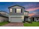 Two-story home with a brick driveway, manicured lawn, and a gray exterior with blue shutters at 4932 Mainsail St, Haines City, FL 33844