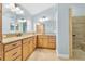 Bathroom showcasing double vanity with granite countertops, light wood cabinets, and tiled walk-in shower at 5810 Penney Ln, The Villages, FL 32163