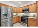 Cozy kitchen featuring stainless steel appliances, granite countertops, and wooden cabinets at 5810 Penney Ln, The Villages, FL 32163