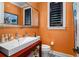 Elegant powder room with orange walls, white sink, and dark wood vanity at 1426 Nottingham St, Orlando, FL 32803