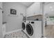 Bright laundry room with white cabinets, washer, dryer, and patterned tile floor at 820 Duff Dr, Winter Garden, FL 34787