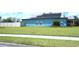 Side view of a bright blue home with solar panels, lush lawn and white privacy fence at 515 Haywood Ln, Lake Alfred, FL 33850