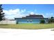 View of a bright blue home with solar panels, lush lawn and white privacy fence at 515 Haywood Ln, Lake Alfred, FL 33850