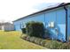 Side view of bright blue house, surrounded by green grass and landscaping at 515 Haywood Ln, Lake Alfred, FL 33850