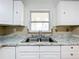 Close-up of the kitchen sink and countertop, featuring granite counters and bright natural light from the window at 201 N East St, Leesburg, FL 34748