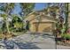 Two story tan house with a large garage surrounded by well manicured landscaping at 2981 Viscount Cir, Kissimmee, FL 34747