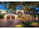 Elegant Spanish-style home with a brick driveway and beautifully lit at night at 541 Virginia Dr, Winter Park, FL 32789