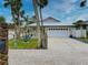 A beach-style home with a white garage door, palm trees, and a gravel driveway at 821 E 1St Ave, New Smyrna Beach, FL 32169