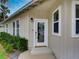 White front door with a decorative glass etching, flanked by windows and shrubs at 821 E 1St Ave, New Smyrna Beach, FL 32169