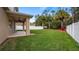 A covered patio leads to a sprawling backyard with palm trees and privacy fencing at 10097 Leland Dr, Orlando, FL 32827