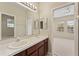 Bathroom featuring double sinks, a large mirror with vanity lighting, and shower with glass door at 10097 Leland Dr, Orlando, FL 32827
