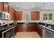 Cozy kitchen featuring wooden cabinets, black countertops, stainless steel appliances and wood-look flooring at 10097 Leland Dr, Orlando, FL 32827