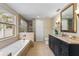 Main bathroom with soaking tub, shower, and dark vanity at 11944 Cheltinham Dr, Orlando, FL 32824
