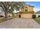 Two-story yellow house with a brick driveway and large tree at 11944 Cheltinham Dr, Orlando, FL 32824
