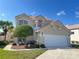 Two-story house with a beige exterior, a two-car garage, and landscaping at 13328 Lake Turnberry Cir, Orlando, FL 32828