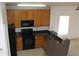 Kitchen with dark countertops, wood cabinets, and black appliances at 13653 Daniels Landing Cir, Winter Garden, FL 34787