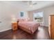 Cozy bedroom featuring a queen bed, dark laminate floors, ceiling fan and natural light from a large window at 26812 Augusta Springs Cir, Leesburg, FL 34748