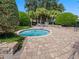 Outdoor hot tub surrounded by brick pavers and lush landscaping, perfect for relaxing at 26812 Augusta Springs Cir, Leesburg, FL 34748