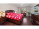 Main bedroom with dark wood floors and bold floral bedding, offering ample natural light and storage at 26812 Augusta Springs Cir, Leesburg, FL 34748